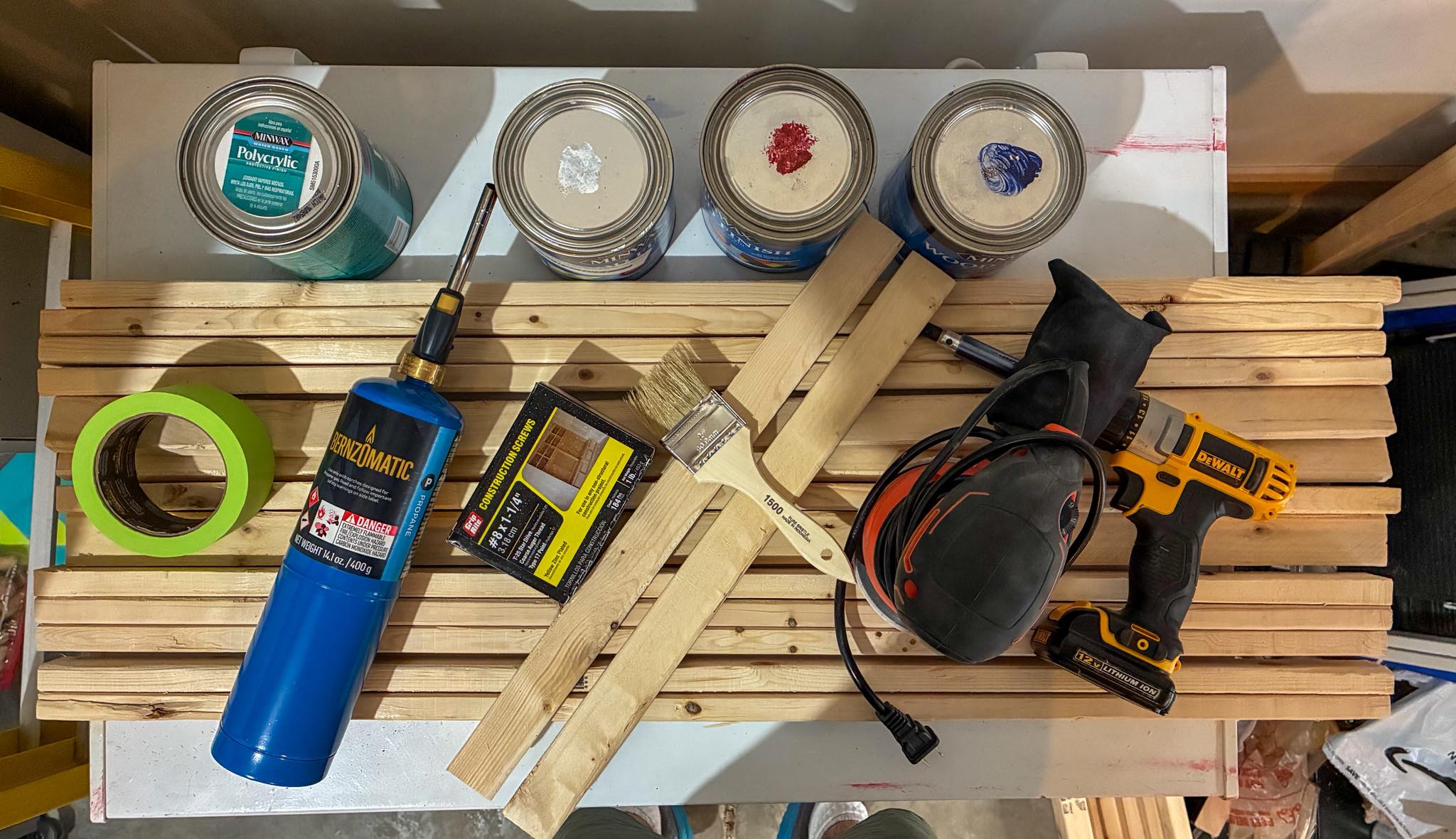 Wood American flag staining supplies - stain, brushes, torch and tools laid out in the workshop