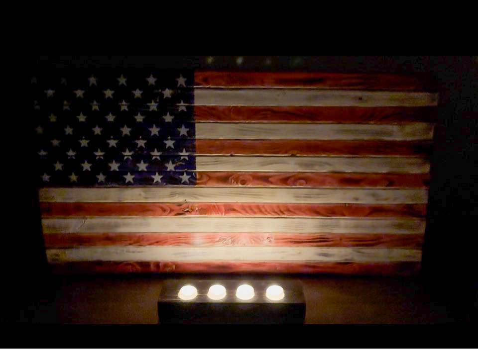 Handcrafted wood American flag glowing in candlelight, a 5th anniversary wood gift
